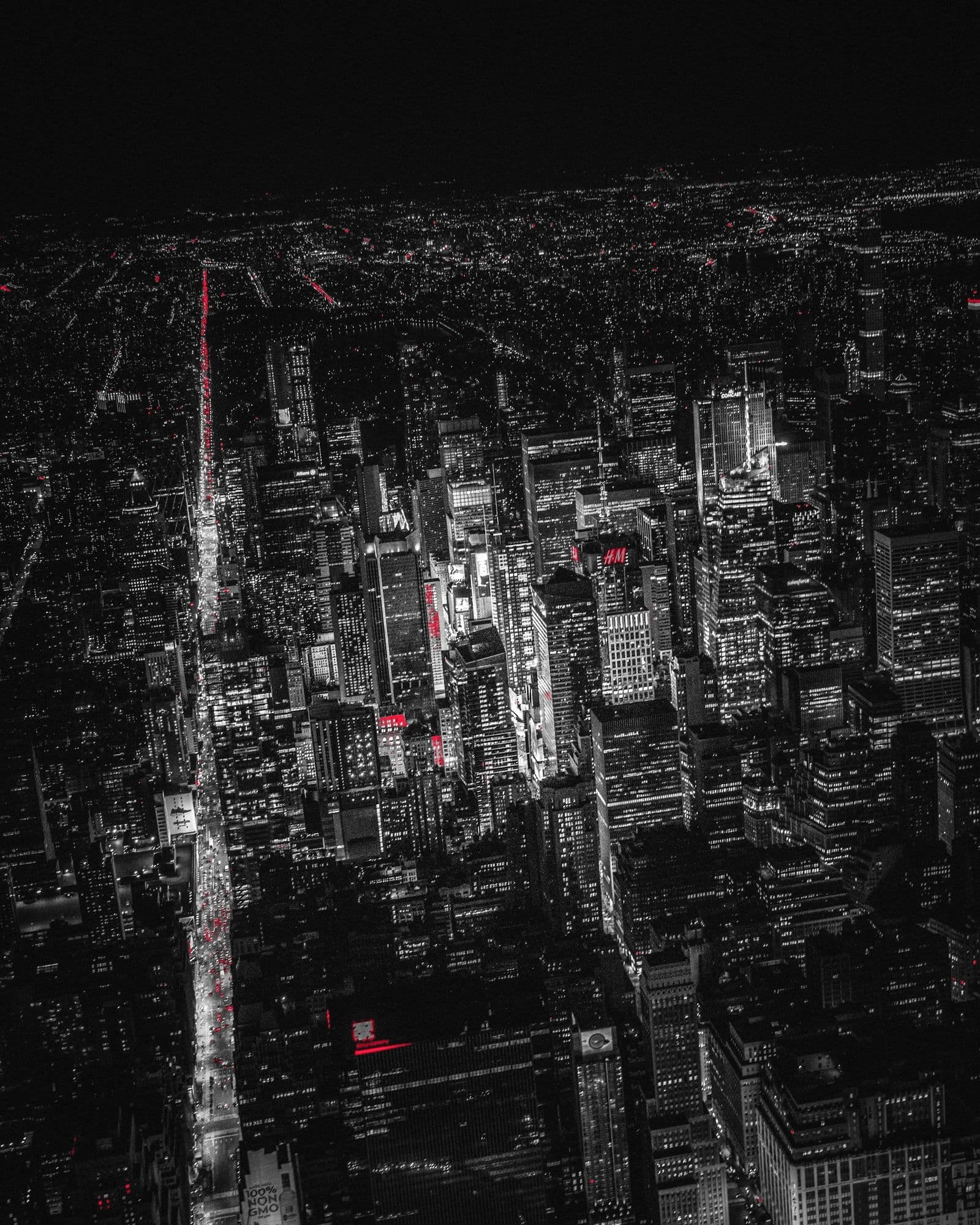 Aerial view of Midtown Manhattan at night, its avenues glowing in a dark grid